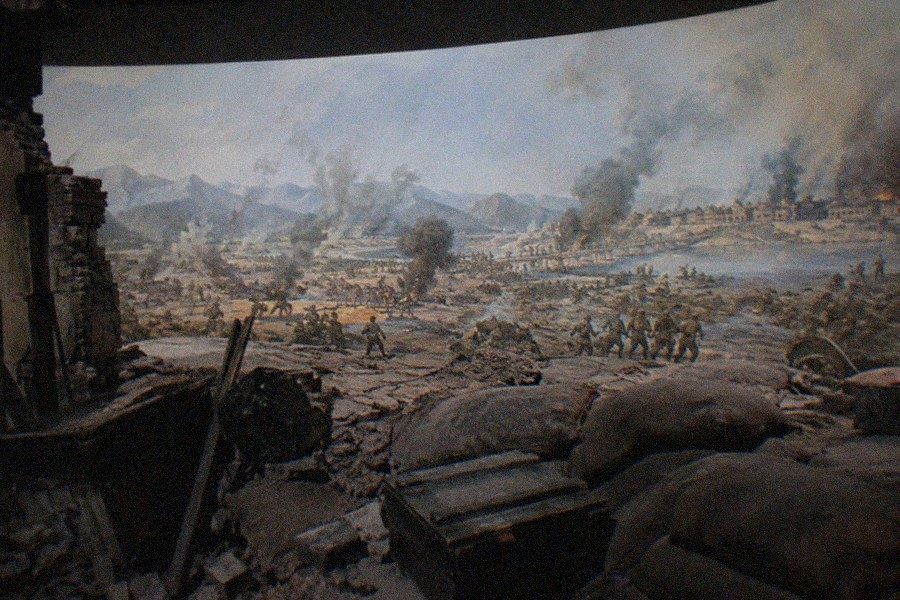Exhibition hall of the Museum of the War of Chinese People’s Resistance Against Japanese Aggression with display cases of wartime rifles, helmets and documents under low lighting