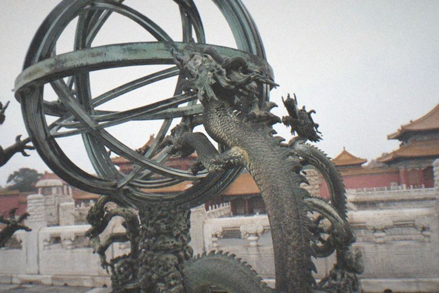 Bronze astronomical instruments mounted on the rooftop platform of the Beijing Ancient Observatory, with the Beijing skyline behind them