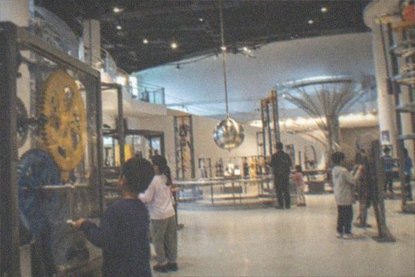 Astronomy exhibit hall with model planets and display cases under dim lighting
