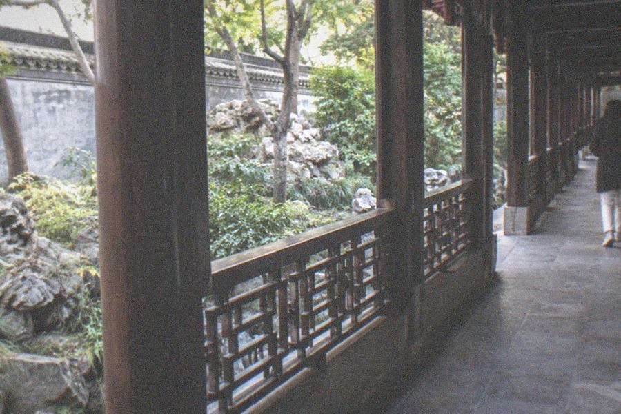 A stone ramp and balustrade leading up to a red-walled hall in evening light