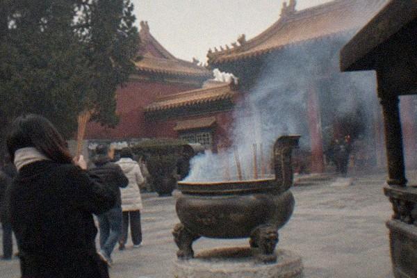 Golden roof finials and red walls of a temple complex under a clear sky