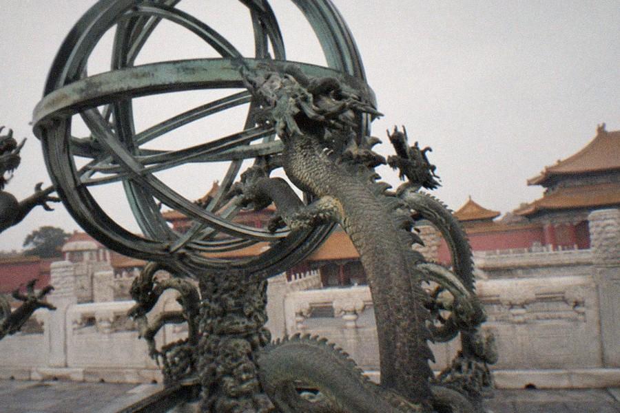 A raised brick observatory platform in Beijing with large bronze astronomical instruments arranged along the terrace edge