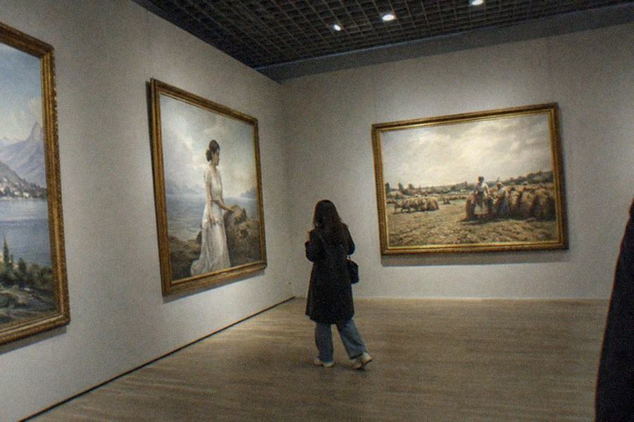 Museum visitors viewing large contemporary canvases in a bright exhibition hall