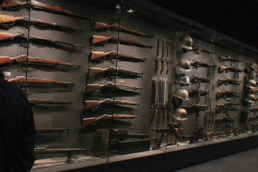 A tall exhibition hall inside the Military Museum of the Chinese People's Revolution with military aircraft suspended overhead and visitors on the floor below